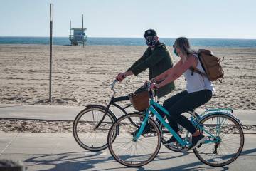 A couple rides bikes near a beach