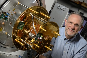 Charles L. Bennett poses with gold and silver WMAP device
