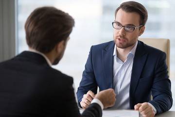 Two men having a civil conversation across a desk