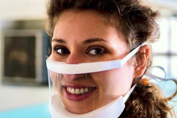 A woman wears a clear plastic mask
