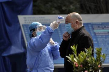A health worker checks a man's temperature before he enters a hospital in China