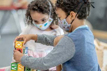 Toddler girl and boy playing at daycare while wearing masks