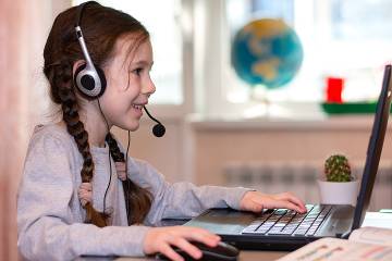 Young girl wearing headphones and working on a laptop