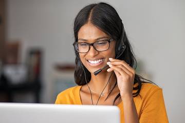 Smiling woman wearing a headset talking with a customer