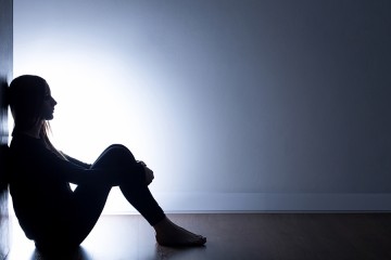 Silhouette of teen girl sitting on floor in darkened room
