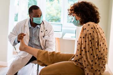 A doctor examines a woman's outstretched leg