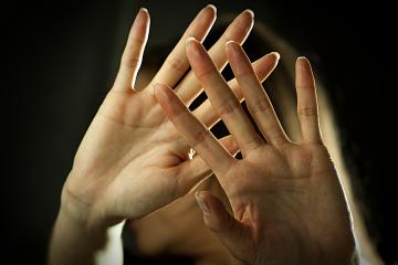 A woman's outstretched open hands protect her face