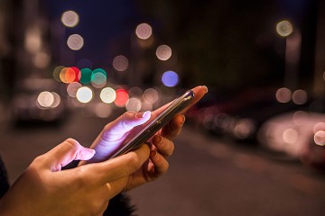 Closeup of a woman's hands using a phone app at night