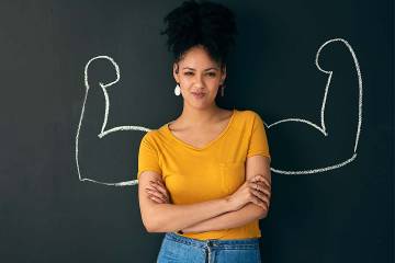 Woman posing in front of a chalk illustration of flexing muscles 