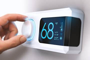 Woman's hand adjusting an indoor thermostat