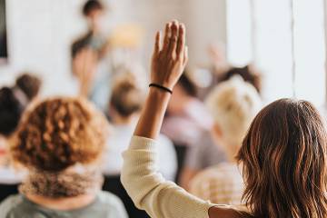 Woman in audience raising her hand to ask a question