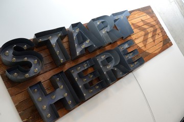 'Start Here' sign on wood background