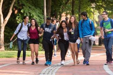 Seven students walk along the quad, arm in arm