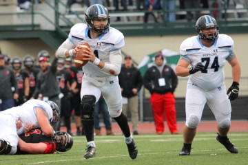 Quarterback runs to his right with both hands on the ball