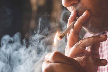 Man lighting a cigarette with smoke in the background