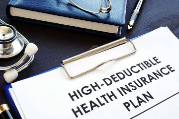 A high-deductible health insurance plan is shown on a desk.