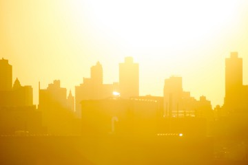 City skyline silhouetted by blazing orange and yellow summer sun
