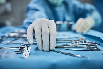 Gloved hand reaches for surgical instruments
