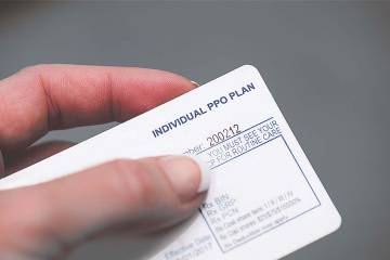 Closeup of a hand holding an insurance card for an individual PPO plan