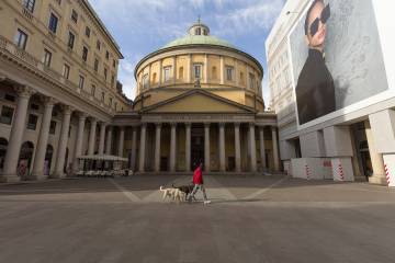 A person walks dogs in front of the Cathedral of San Carlo al Corso, Milan, Italy