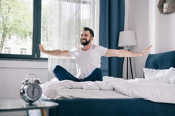 Happy man stretching his arms when he wakes up