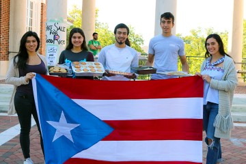 Puerto Rico JHU students hold Puerto Rican flag and trays of bakes goods.