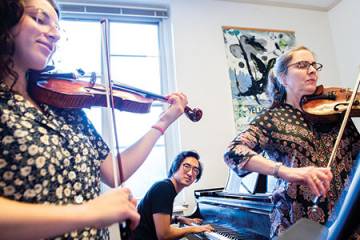 A violinist, a violist, and a pianist practice a performance