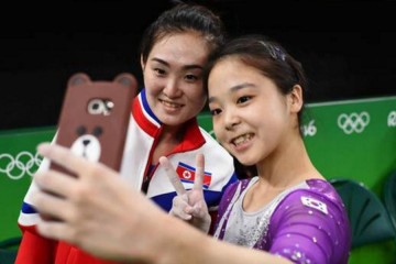 Two woman pose for a selfie taken with a camera with a bear case.