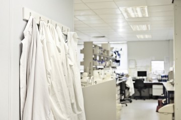 A row of lab coats hang on hooks in a lab