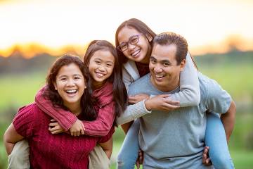 Smiling mother and father carrying their young daughters piggyback