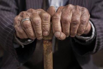Close-up image of an old man holding a cane