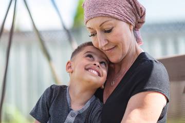 Serious-looking woman with head wrap holding her child