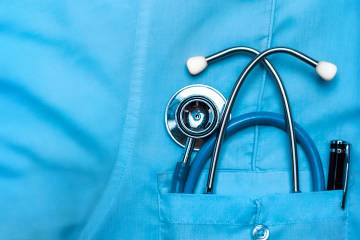 Stethoscope and pen in doctor's robe chest pocket