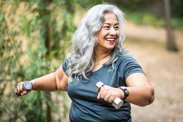 Woman exercizes with hand weights outdoors
