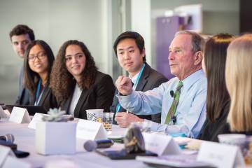 Michael R. Bloomberg seated a table with students