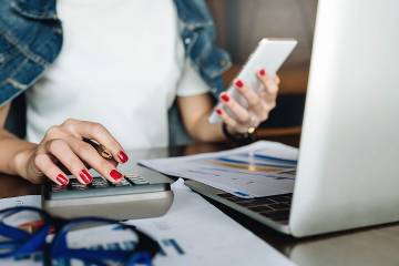 Woman using calculator with phone in her other hand