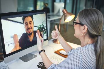 Counselor gives thumbs up to young man appearing on her computer screen