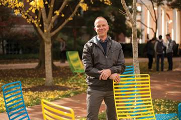 Photograph of Chris Nealon standing next to neon lawn chairs