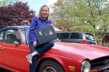 Pat Conklin sitting on the hood of an old sports car outside her home in Hamilton