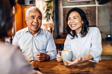 Happy senior couple visiting with a friend in a coffee shop