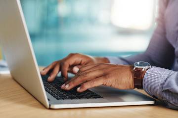 Closeup of man's hands using a laptop in an office