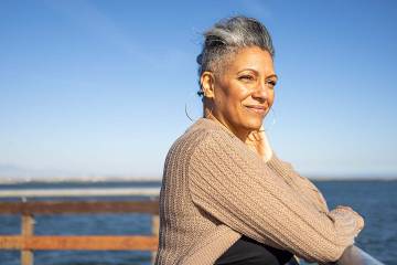 A mature Black woman relaxing on a pier overlooking water.