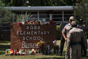 Flowers are laid by the sign for Robb Elementary School in Uvalde, Texas, after a mass shooting there claimed the lives of 21 people