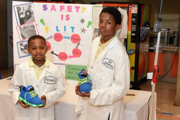 Two students hold up their LED sneaker prototypes