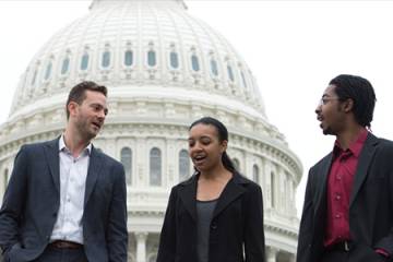 Three people in conversation, with the U.S. Capitol dome in the background