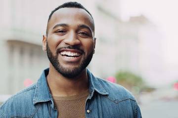 Happy smiling young man. He's wearing a casual sweater and a denim jecket.