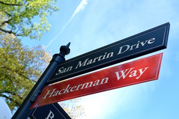 Hackerman Way on red street sign under dark blue San Martin Drive sign