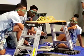 Student team hangs weights from a spaghetti bridge