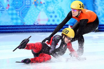 A short track speed skater falls in front of another skater