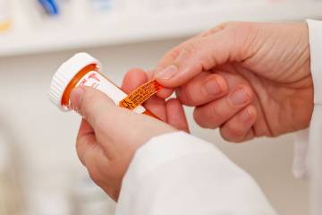 Pharmacist applying a drug-warning label to a pill container